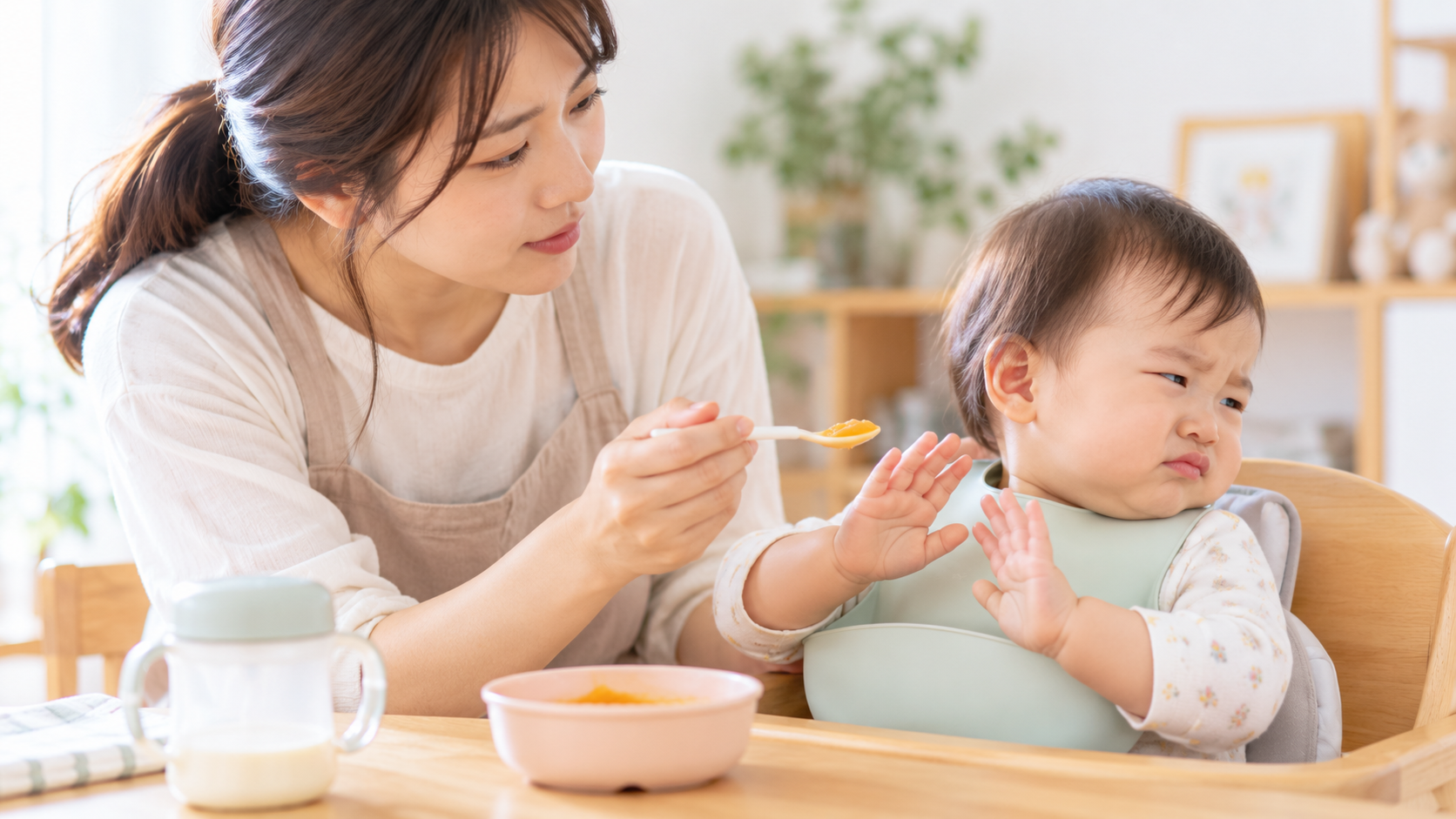 離乳食を食べたくない様子の赤ちゃんを見守る保護者のイメージ